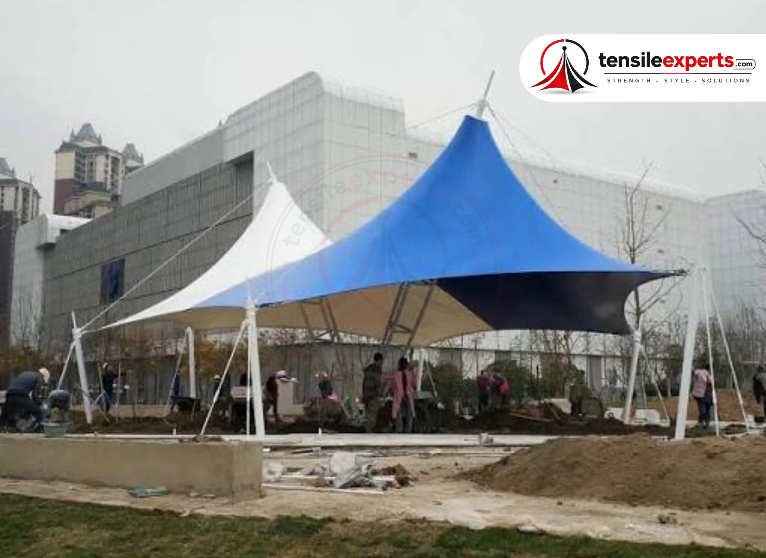 Multiple tensile cone structures under construction, showing the central-mast framework.