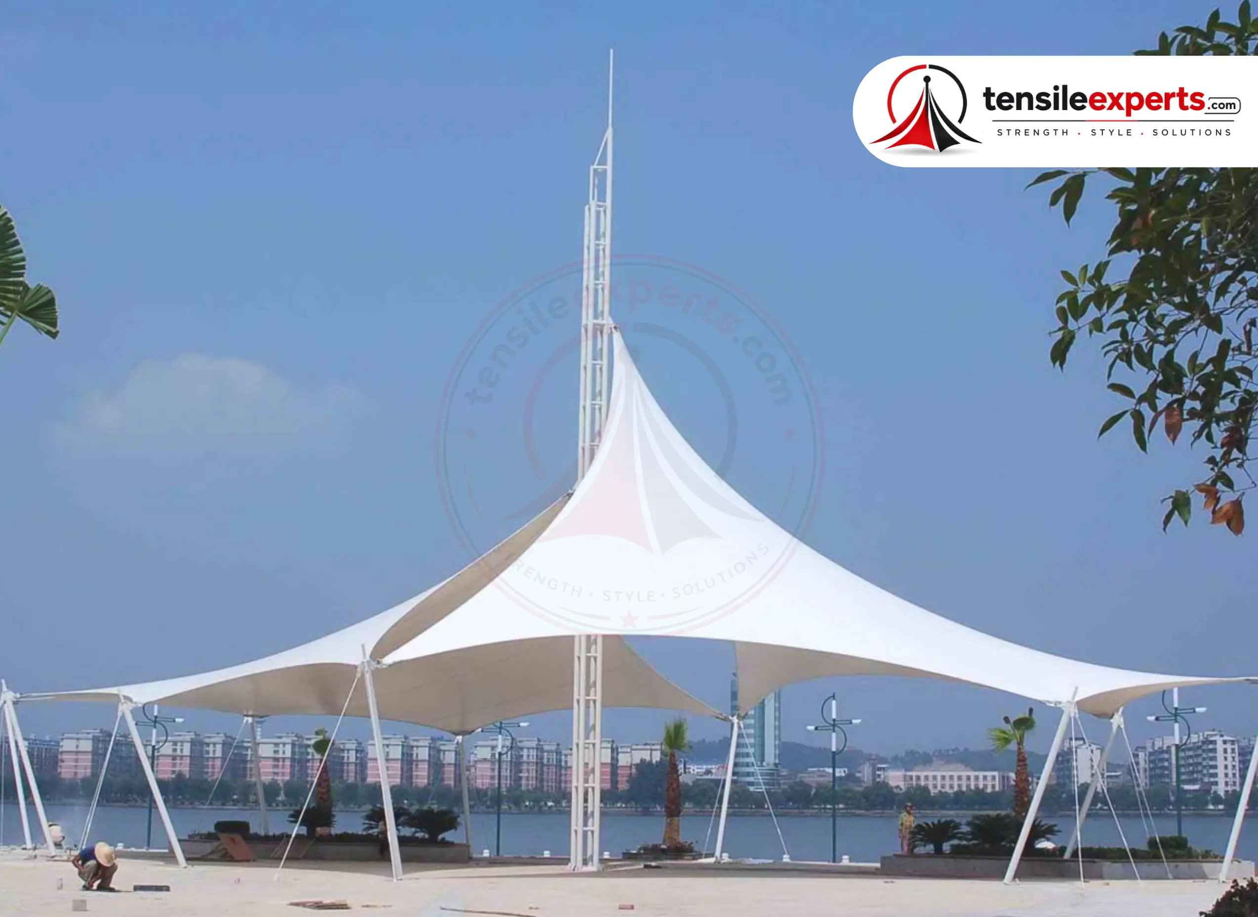 A tensile fabric structure by a lakeside — the same custom-engineered approach fits a manufacturing site's specific production-floor footprint.