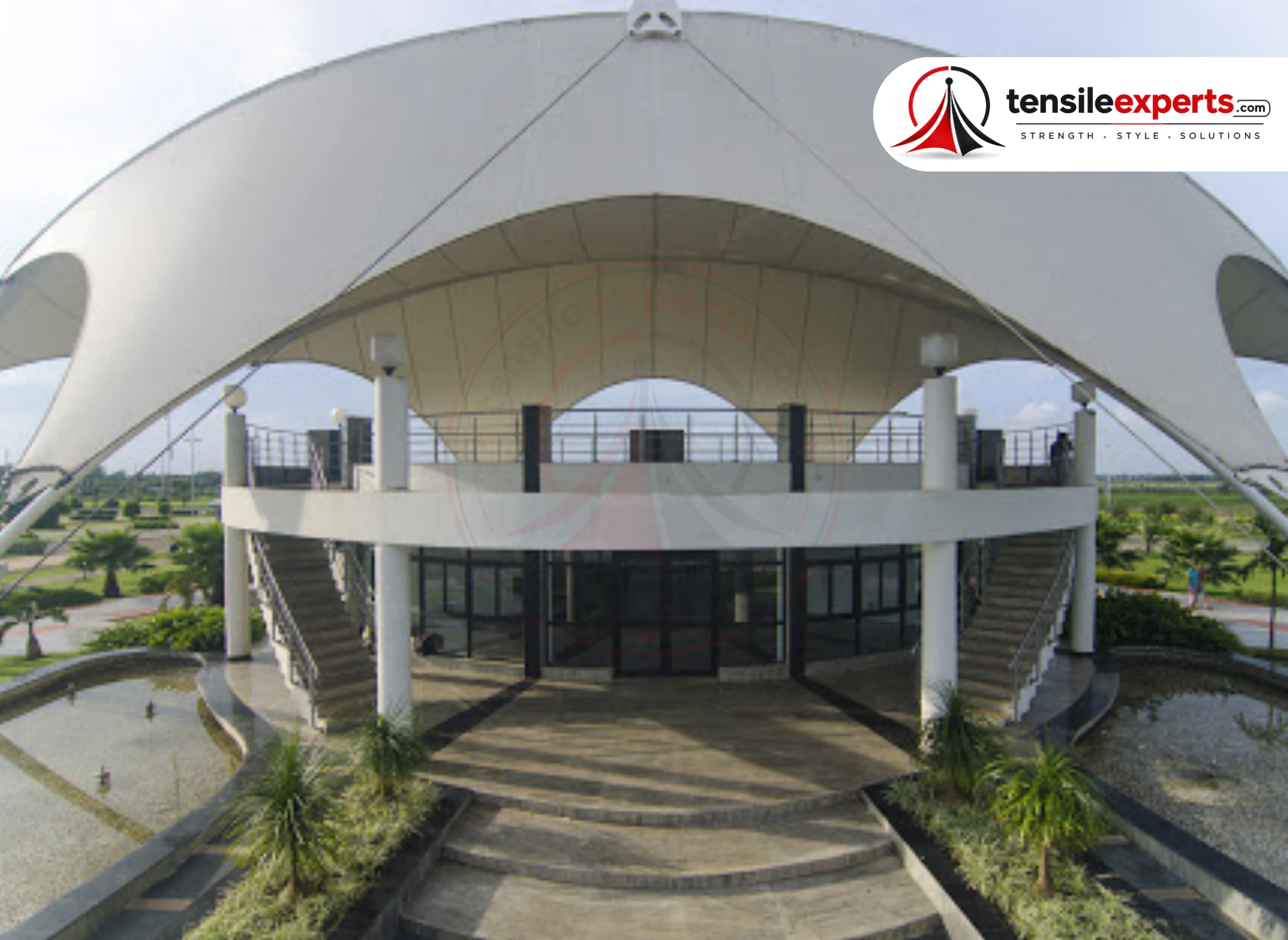 A large tensile canopy over a commercial building's entrance staircase and gathering area.