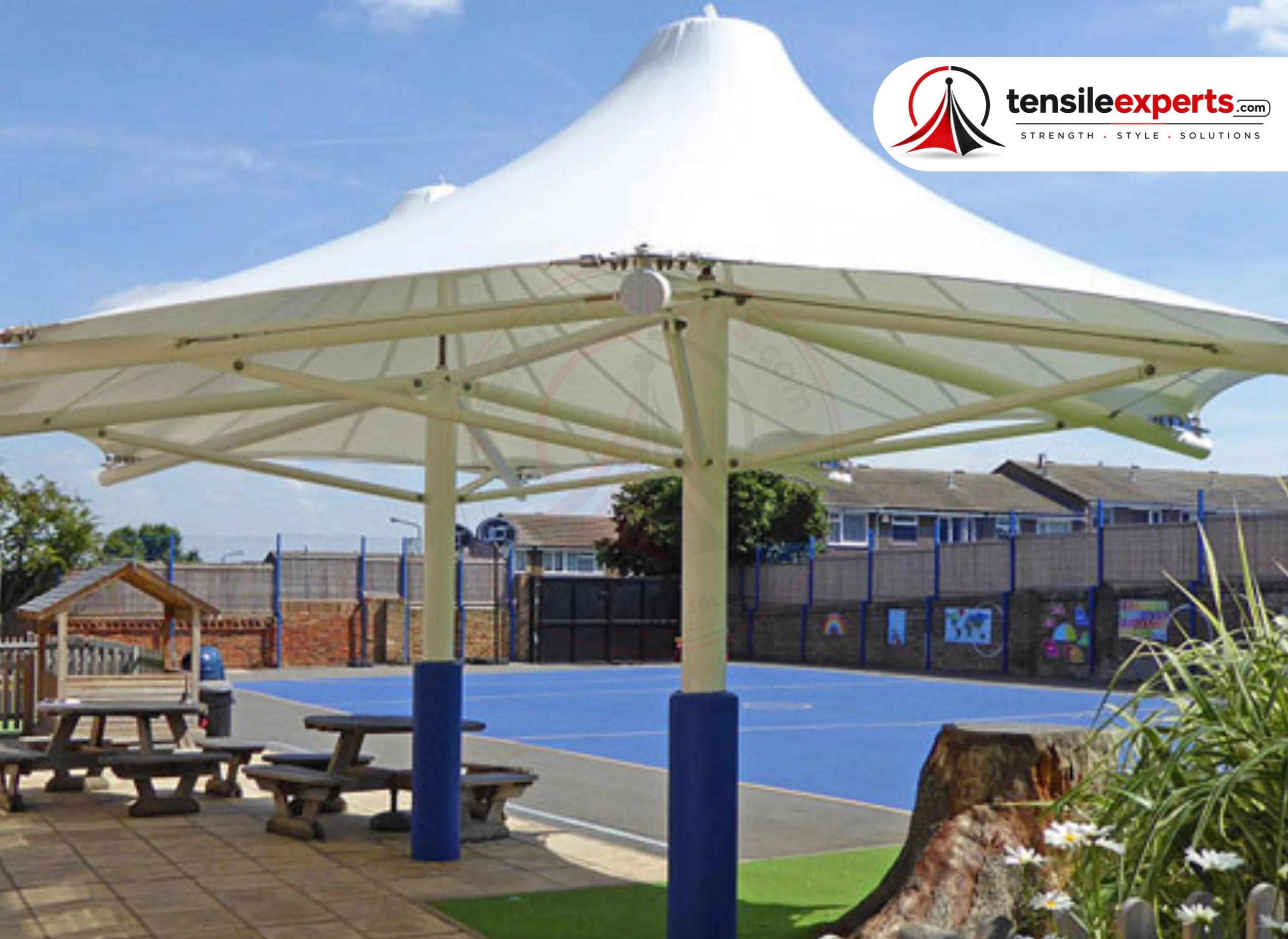 A double-cone tensile gazebo over a school playground seating area.