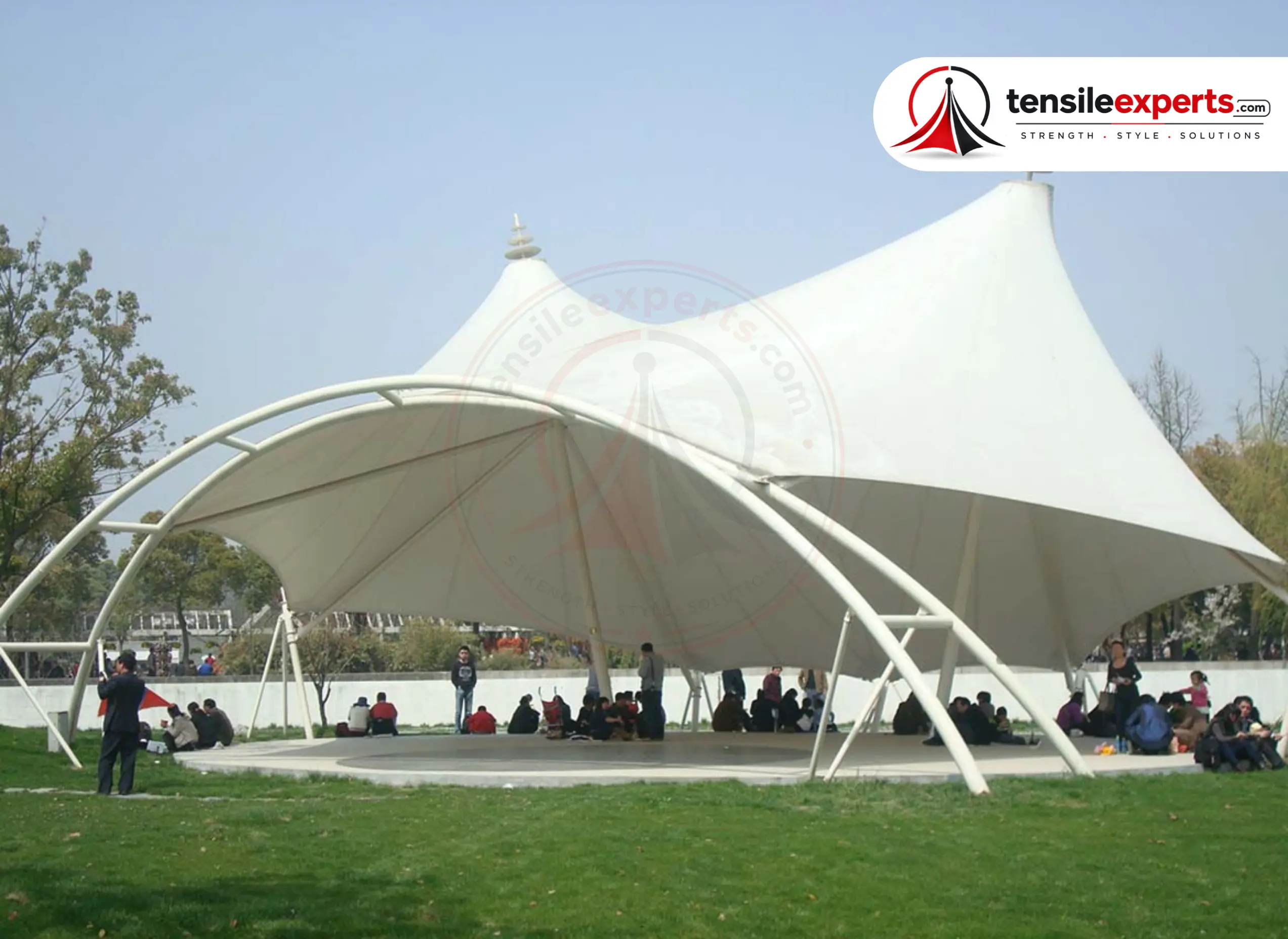 A large-span tensile membrane structure over a public park gathering space.