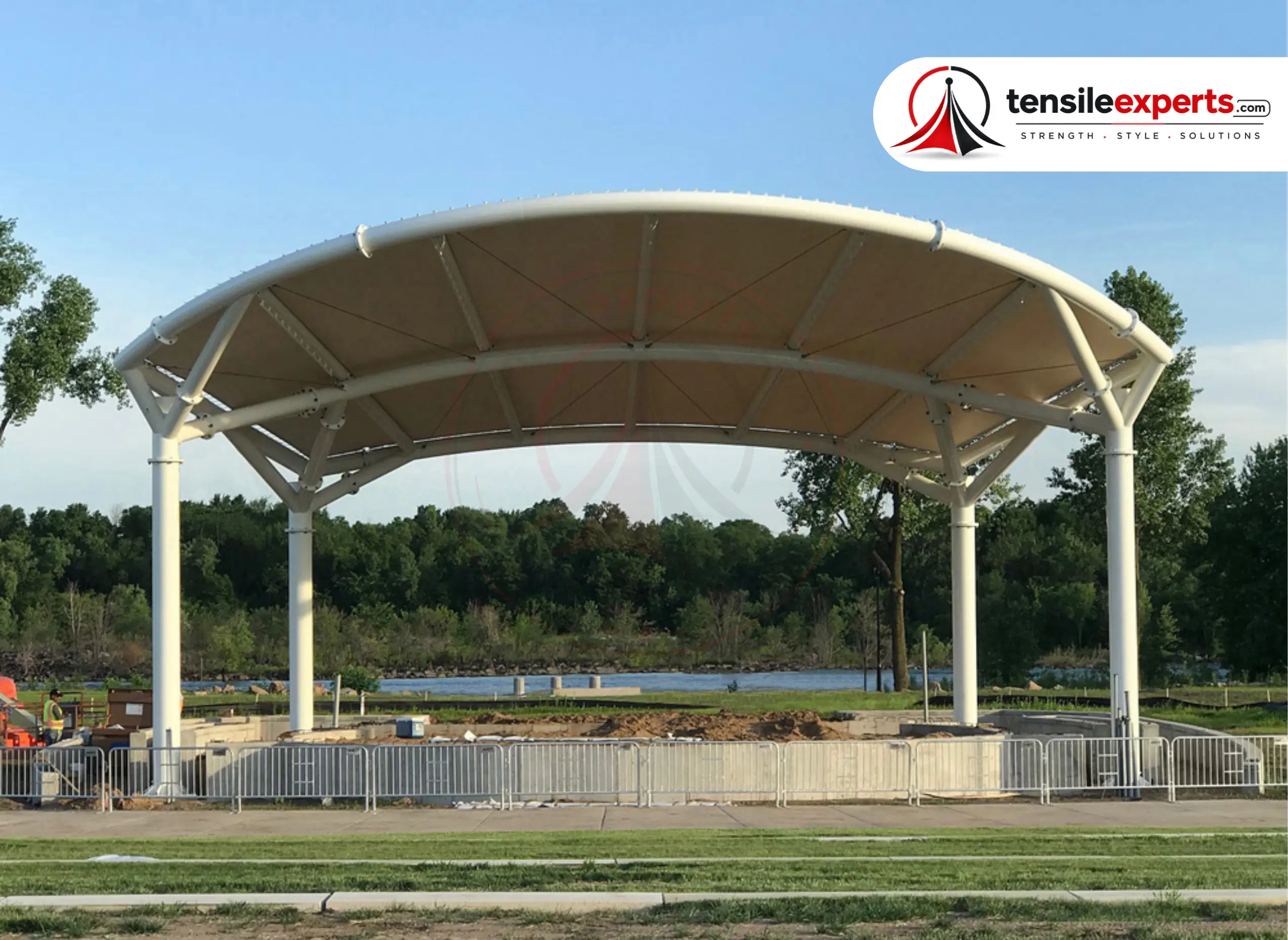 A large-span tensile roof structure under construction at a lakeside public park.