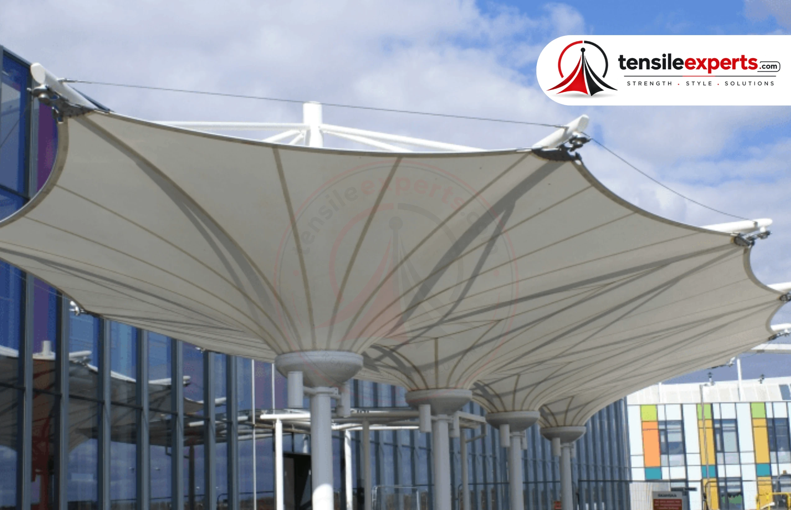 A multi-unit tensile umbrella structure — several single-column units spaced across a seating area.