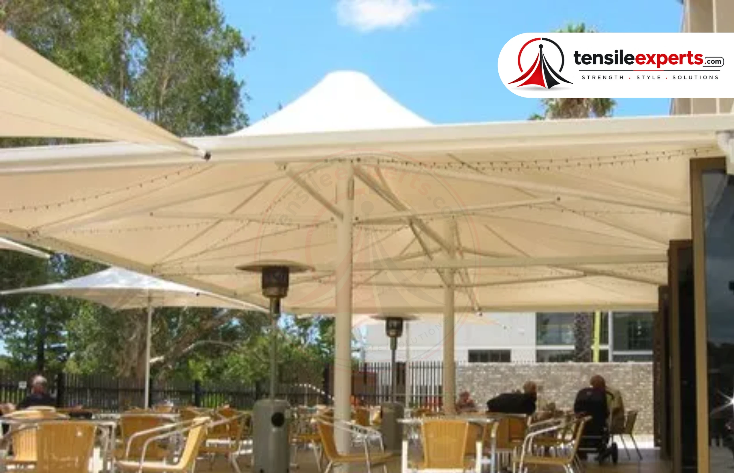 Large umbrella-form tensile canopies over an outdoor café seating area